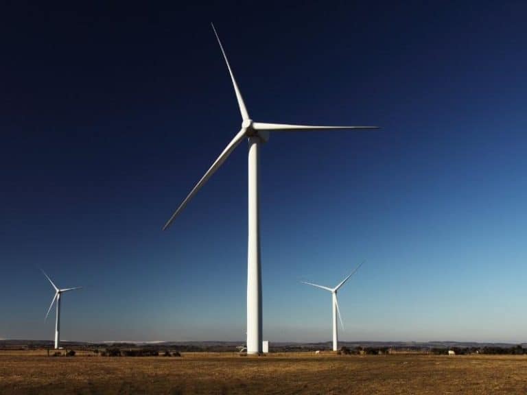 Large commercial wind turbines on grass with a blue sky